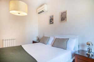 um quarto com uma cama branca e um candeeiro em R&B MUNTANER em Barcelona