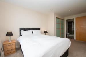 um quarto com uma grande cama branca e uma casa de banho em Blue Harbour Apartments em Edimburgo