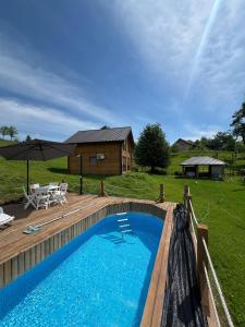 a swimming pool with a wooden deck and a house at Vikendica Brvnara Marčetić in Banja Luka