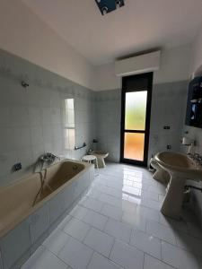 Mutignano的住宿－La Foresteria- Azienda agricola Garra，浴室配有2个盥洗盆、浴缸和盥洗盆。