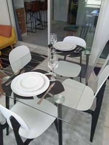 a glass table with white plates and wine glasses on it at Studio Vanille - Vue Mer in Saint-Denis