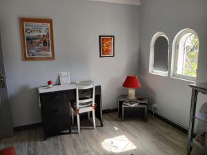 a room with a desk and a table with a lamp at Appartement indépendant privatif avec jardin in Le Crès