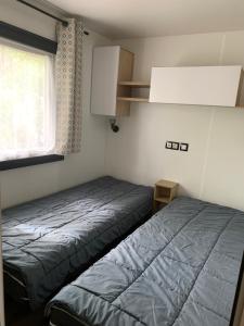 mała sypialnia z dwoma łóżkami i oknem w obiekcie MH 008 Bora Bora sur emplacement exceptionnel en lisière de forêt dans camping 4 étoiles w mieście Saint-Julien-en-Born