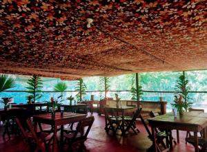 restauracja ze stołami i krzesłami oraz dużym oknem w obiekcie Jungle Explorer Lodge w mieście Mazán