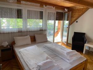 a large white bed in a room with windows at Petőfi24 Apartmanok in Siófok