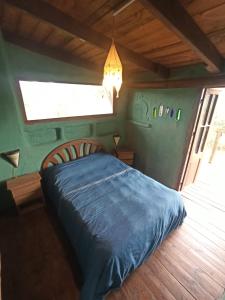 1 dormitorio con 1 cama con edredón azul y ventana en Odisea, en Villa Serrana