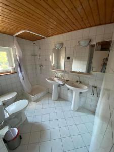 a bathroom with two sinks and a shower and a toilet at Petőfi24 Apartmanok in Siófok