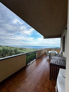 balcón con mesa, sillas y vistas al océano en La Foresteria- Azienda agricola Garra en Mutignano