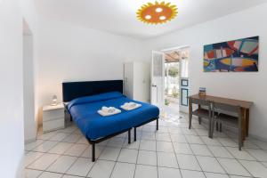 Schlafzimmer mit einem blauen Bett und einem Schreibtisch in der Unterkunft Margherita House in Procida