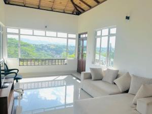 a living room with a white couch and a window at Rockview Gardens Homestay in Kandy