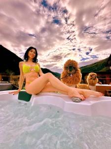 een vrouw aan de rand van een zwembad met twee honden bij Nira Mountain Resort Futura in Valdidentro