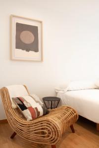 1 dormitorio con silla de mimbre y 1 cama en Progreso Sanxenxo, en Sanxenxo
