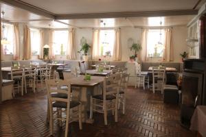 a restaurant with white tables and chairs and windows at Landgasthof Doldewirt in Bernbeuren