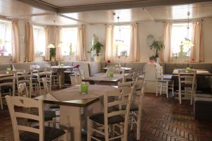 un restaurante con mesas, sillas blancas y ventanas en Landgasthof Doldewirt en Bernbeuren
