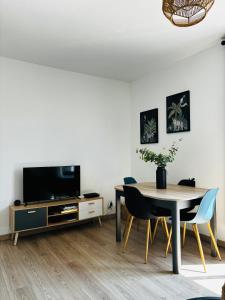uma sala de jantar com uma mesa e uma televisão em 15 mn de PARIS, perle rare avec vue - 2 chambres em Groslay