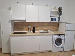a kitchen with white cabinets and a washer and dryer at MYRA Holiday in Syracuse +40 photos