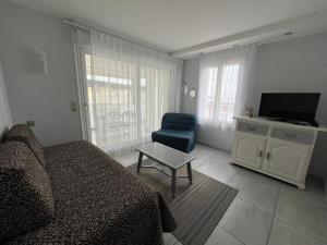 a living room with a bed and a tv and a chair at H&ocirc;tel Valencia in Hendaye