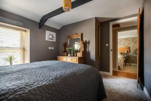 Schlafzimmer mit einem Bett und einem Spiegel in der Unterkunft The Cottage - Characterful, coastal family home with new hot tub in Dawlish