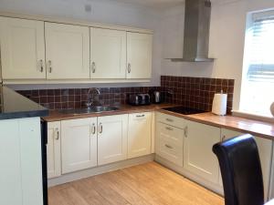 a kitchen with white cabinets and a sink at Yarm Serviced Apartments in Yarm +8 photos