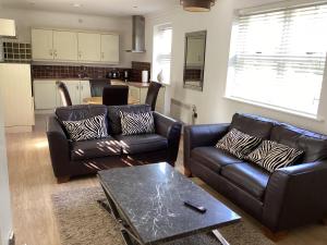 a living room with two leather couches and a table at Yarm Serviced Apartments in Yarm