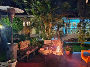 a porch with a hammock and palm trees and a fire at Mazzola Safari House & Backpacking in Arusha
