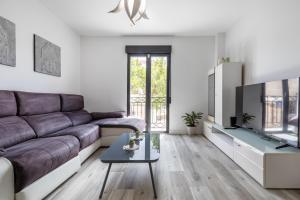 ein Wohnzimmer mit einem Sofa und einem TV in der Unterkunft Apartamento moderno a 10 minutos del centro in Ogíjares