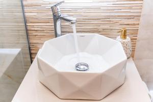 Un lavabo blanco con grifo en un baño. en Feel the Paris with C&A apartment - By OpenHouse, en Timisoara 44 fotos más