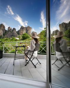 two women sitting in chairs on a balcony looking at the mountains at Boutique St Stephens Residence in Kalabaka