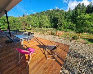 una terraza de madera con mesa y sillas. en Lawendowy Staw, en Cisna