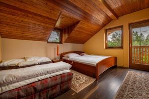 2 camas en una habitación con techos y ventanas de madera en VILA LIMACO JASENSKÁ DOLINA PRI MARTINE en Horné Jaseno