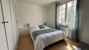 um quarto branco com uma cama e uma janela em Maison le Vent du Large em Sibiril