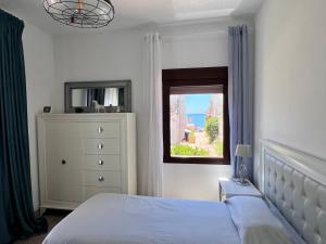 1 dormitorio con cama, ventana y vestidor en Pirata Bungalow sea front, en Estepona