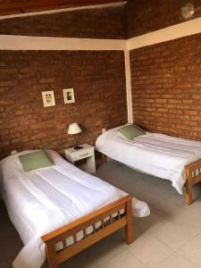 2 camas en una habitación con una pared de ladrillo en Departamentos Nqn Equipados en Neuquén