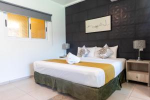 a bedroom with a large bed with a black wall at Hotel Scarlette in Tulum