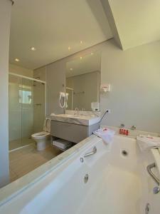 uma casa de banho com uma banheira, um lavatório e um WC. em Flats Chateau Campos do Jordão em Campos de Jordão