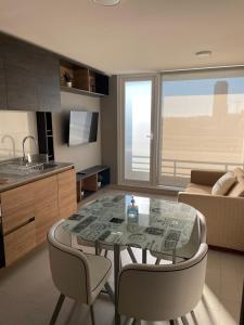 a kitchen and living room with a glass table and chairs at Departamento Tucapel 2 centro de Concepción in Concepción