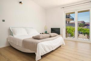 ein weißes Schlafzimmer mit einem großen Bett und einem Balkon in der Unterkunft Apartments Vitis in Vodice