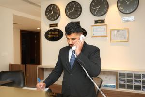 un hombre hablando por teléfono mientras hablaba por teléfono en Noor Amwaj Hotel & Apartment en Manama