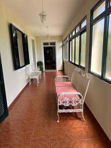 Un pasillo con sillas blancas y un banco rojo. en Elisabeth House, en Ponta do Sol