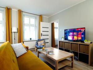 - un salon avec un canapé jaune et une télévision dans l'établissement Apartamenty KDN na Rysiej, à Katowice