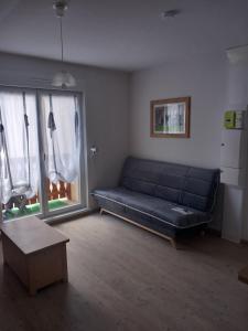 - un salon avec un canapé noir et des fenêtres dans l'établissement Résidence de Tourisme La Meije Blanche, à Villar-dʼArêne