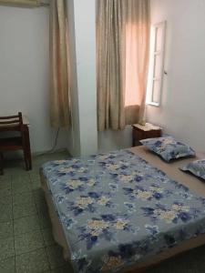 una camera da letto con un letto con un piumone blu e una finestra di Hotel de la plage a Bizerte