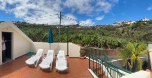 Un balcón con sillas blancas y una valla. en Elisabeth House, en Ponta do Sol