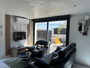 - un salon avec deux fauteuils en cuir et une télévision dans l'établissement T&A Lodge AVEC SPA JACUZZI à 11km de la plage, à Solliès-Pont