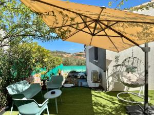 une terrasse avec une table, des chaises et un parasol dans l'établissement T&A Lodge AVEC SPA JACUZZI à 11km de la plage, à Solliès-Pont