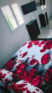 a bedroom with a bed with red flowers on it at La Villa Marcel in Le Barcarès