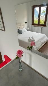 un espejo que refleja un dormitorio con una cama y flores en un jarrón en Garda View Apartment, en Tenno