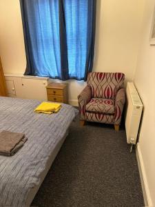 a bedroom with a bed and a chair and a window at Luton Town House Near AIRPORT in Luton