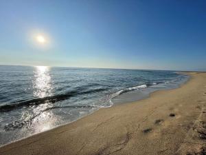 a beach with the sun reflecting on the water at La Villa Marcel in Le Barcarès