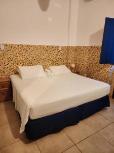 a bedroom with a large bed with white sheets at Pousada Solar Azul in Lençóis